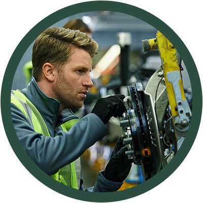 Man in high-vis vest looking at car brake system