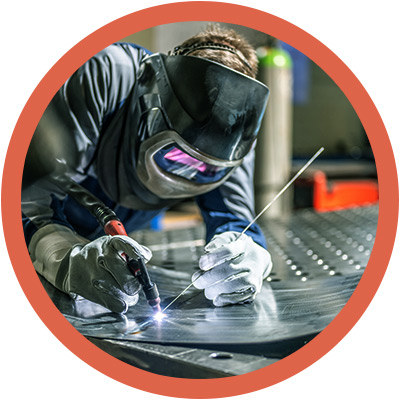 Worker in welding mask working on sheet metal